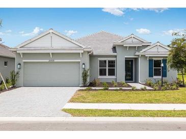 Beautiful single-story home featuring a manicured lawn, gray exterior, and a two-car garage at 26908 Victoria Pl, Punta Gorda, FL 33955