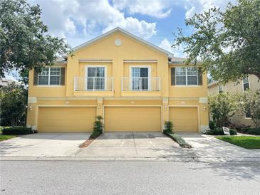Three unit townhome with yellow exterior, balconies, and matching garage doors at 6768 Breezy Palm Dr, Riverview, FL 33578