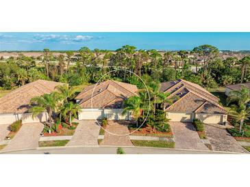 Charming townhome featuring a tile roof, a two-car garage, and lush landscaping at 20170 Benissimo Dr, Venice, FL 34293
