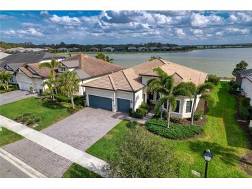 Stunning lakefront home features lush landscaping, tile roof, and a paver driveway at 7760 Grande Shores Dr, Sarasota, FL 34240