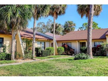 Charming villa with a red tile roof surrounded by mature landscaping and palm trees at 3629 Longmeadow # 38, Sarasota, FL 34235