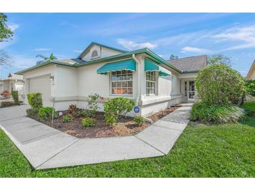 Charming home exterior with manicured landscaping, awning-covered windows, and a paved walkway at 4410 Murfield E Dr, Bradenton, FL 34203