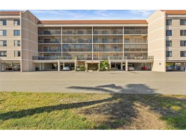 Stunning low-angle shot of a tan five story condo complex with a red tile roof, balconies and well manicured entry at 25188 Marion Ave # E208, Punta Gorda, FL 33950