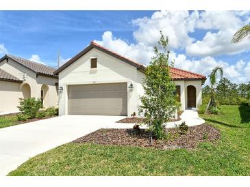 Charming single-story home with a well-manicured lawn and a two-car garage and a red tile roof at 309 Potenza Loop, Nokomis, FL 34275