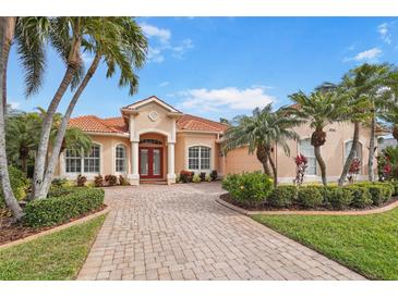 Charming home features a red tile roof, brick driveway, lush landscaping, and stately palm trees at 4245 Corso Venetia Blvd, Venice, FL 34293