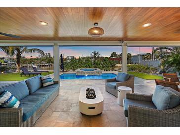 Covered patio with water views, inviting furniture, an outdoor fireplace, and wood plank ceiling at 504 Bayview Dr, Holmes Beach, FL 34217