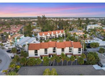An aerial view showcases a condo complex with a red tile roof surrounded by lush green vegetation at 6790 Sarasea Cir # 6790, Sarasota, FL 34242