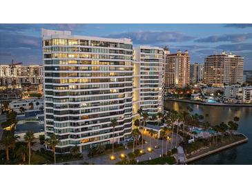 Stunning waterfront condominium with palm trees, lush landscaping, and resort-style amenities at dusk at 888 Blvd Of The Arts # 1008, Sarasota, FL 34236