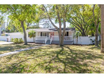 Charming single-story home with a welcoming front porch and beautiful mature trees in a lush, green yard at 916 Michigan Ave, Palm Harbor, FL 34683