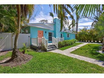 Charming home with a well-manicured lawn, palm trees and quaint walkway leading to a peach colored front door at 115 24Th W St, Bradenton, FL 34205