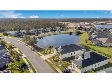Beautiful aerial view of a neighborhood featuring a pond and well-maintained landscaping under a blue sky at 3831 Creekside Park Dr, Parrish, FL 34219