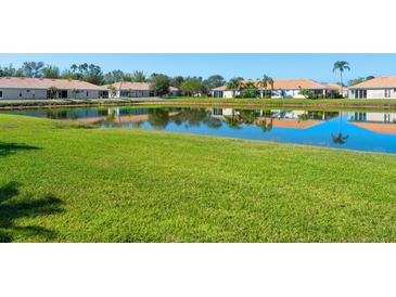 Scenic view of a tranquil pond reflecting nearby homes, surrounded by a lush green lawn at 4155 Cascade Falls Dr, Sarasota, FL 34243