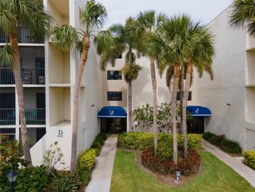 View of a light colored building exterior showing well manicured tropical landscaping and palms at 6116 43Rd W St # 204D, Bradenton, FL 34210