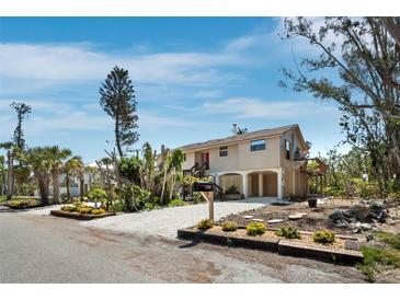 Beautiful home with a sandy driveway and well-manicured landscaping with a red front door and covered parking at 650 Penfield St, Longboat Key, FL 34228