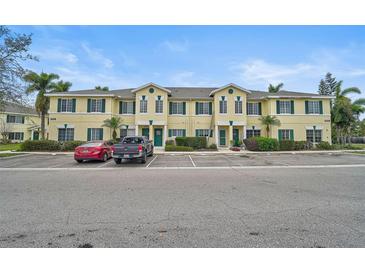 Inviting two-story townhome featuring green shutters, lush landscaping, and ample parking spaces at 208 Cape Harbour Loop # 108, Bradenton, FL 34212