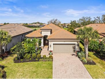 Charming single-story home featuring a tile roof, manicured landscaping, and a welcoming brick driveway at 13908 Messina Loop, Bradenton, FL 34211