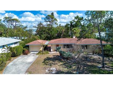 Charming single-story home with a terracotta tile roof and lush tropical landscaping at 1555 Flower Dr, Sarasota, FL 34239