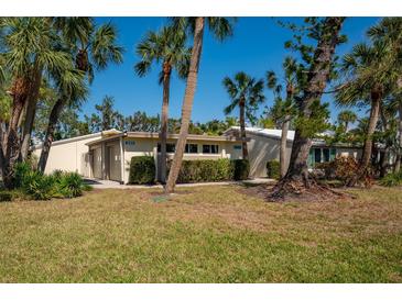 Charming single-story home featuring tropical landscaping, a well-manicured lawn, and a welcoming facade at 231 Hourglass Way # V5, Sarasota, FL 34242