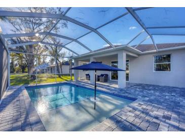 A screened pool with a sun umbrella, chairs, and a paved patio that offers a resort-style experience at 4529 Crowell Ln, North Port, FL 34288