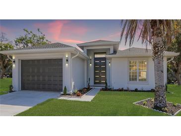 Charming single-story home with a well-manicured lawn, a gray garage door, and a modern front door at 1471 Palmwood Dr, Sarasota, FL 34232