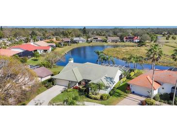 Stunning aerial view of a home with lush landscaping and a serene lake backdrop offering a peaceful neighborhood setting at 3445 Highlands Bridge Rd, Sarasota, FL 34235