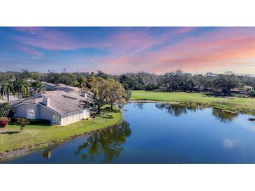 Beautiful home exterior with golf course view, lush trees, and a serene lake at sunset at 4060 Penshurst Park, Sarasota, FL 34235