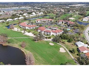 Scenic aerial view of a condo community, featuring a golf course and pond at 6501 Stone River Rd # 205, Bradenton, FL 34203