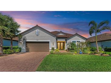 Charming single-story home featuring a well-manicured lawn, mature landscaping, and a brick driveway at 15209 Montello Way, Bradenton, FL 34211