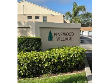 Pinewood Village community sign amidst lush greenery and landscaping at 2607 Woodgate Ln # K9, Sarasota, FL 34231