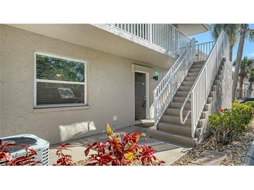 Inviting condo exterior with staircase leading to the upper level and lush landscaping at 966 La Costa Cir # 1, Sarasota, FL 34237