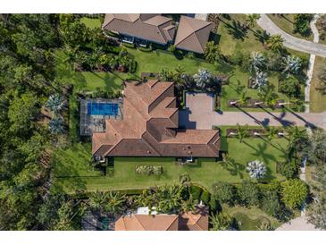 Expansive aerial view of tile roofed home, pool, lush landscaping, and circular brick driveway at 19424 Ganton Ave, Lakewood Ranch, FL 34202