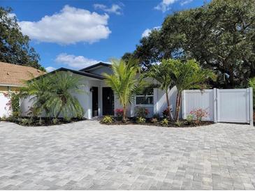 Charming single-story home featuring a beautifully landscaped front yard with a brick driveway, green plants, and a white fence at 1041 S Tuttle Ave, Sarasota, FL 34237