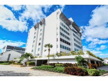 Low angle view of a white condo building against a blue sky with landscaping in the foreground at 1125 W Peppertree Dr # 706, Sarasota, FL 34242