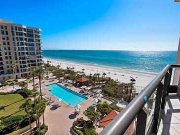 Stunning view of the pool and beach from a high-rise condo with palm trees and lounge chairs at 1281 Gulf Of Mexico Dr # 703, Longboat Key, FL 34228