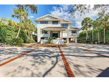 Stunning two-story white home featuring a spacious driveway and lush landscaping, offering curb appeal at 3977 Roberts Point Rd, Sarasota, FL 34242