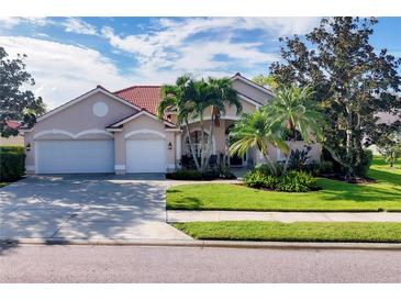 Charming single-story home with a red tile roof, manicured lawn and mature palm trees at 4705 Sweetmeadow Cir, Sarasota, FL 34238