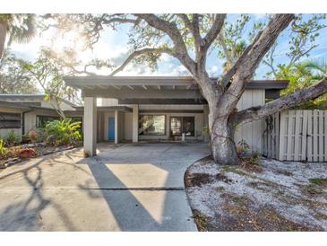 Inviting single-story home featuring covered parking and a mature tree providing shade and curb appeal at 4710 Gleason Ave, Sarasota, FL 34242