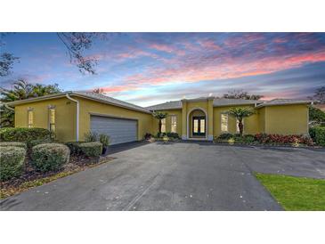 Charming single Gathering home with a two-car garage, arched entrance, and neatly landscaped yard at 6114 Misty Oaks St, Sarasota, FL 34243