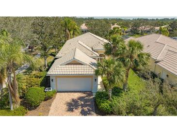 Charming single-story home with a well-manicured lawn, brick driveway, and tile roof at 8300 Jesolo Ln, Sarasota, FL 34238