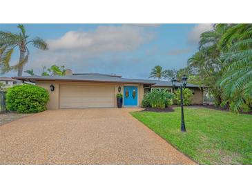 Charming home with a well-manicured lawn, lush landscaping, and a welcoming blue front door at 940 Siesta Key Pl, Sarasota, FL 34242