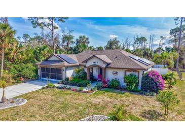 Beautifully landscaped single Gathering home with a well manicured lawn and solar panels on the roof at 2625 Yuma Ave, North Port, FL 34286