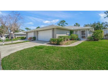 Charming single story villa with a one car garage, lush green grass, and mature landscaping at 3919 Center Gate Cir # 10, Sarasota, FL 34233