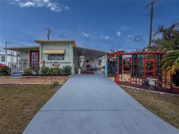 Charming home featuring a long driveway leading up to a red-doored home with colorful flowers and a trellis covered patio at 4103 12Th Street E Ct, Ellenton, FL 34222