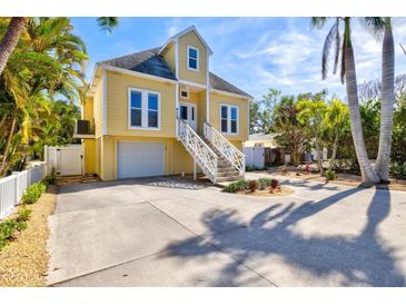 Charming two-story yellow home featuring a white staircase, lush landscaping, and an attached garage with a spacious driveway at 4117 Roberts Point Cir, Sarasota, FL 34242