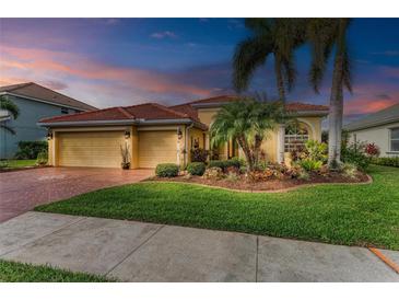 Charming home featuring a well-manicured lawn, beautiful landscaping, red-tiled roof and a three-car garage at 9039 Willowbrook Cir, Bradenton, FL 34212