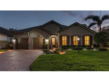 Charming single-story home with a manicured lawn and a brick driveway at dusk at 10406 Eastwood Dr, Bradenton, FL 34211