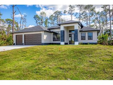 Beautiful single-story home featuring a three-car garage and a well-manicured lawn at 12495 Patsy Ave, Port Charlotte, FL 33981