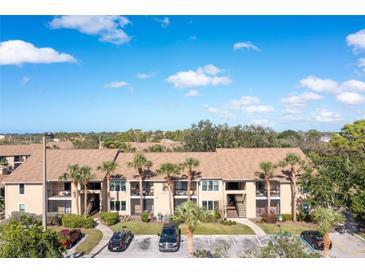 Beige two-story condo building featuring palm trees and a parking lot in a sunny, tropical setting at 4008 Crockers Lake Blvd # 13, Sarasota, FL 34238