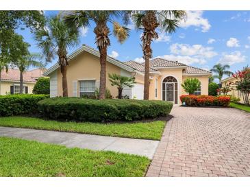 Charming single-story home featuring a well-manicured lawn, paver driveway, and lush tropical landscaping at 5539 Octonia Pl, Sarasota, FL 34238