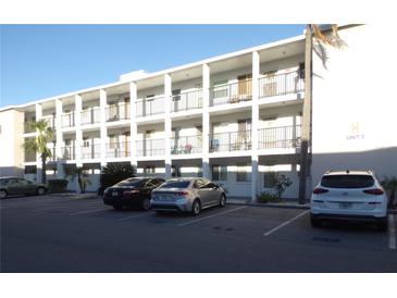 Three-story condo building featuring white paint, balconies, and ample parking for residents and guests at 5889 Garden Ln # H4, Bradenton, FL 34207